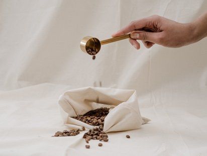A person is pouring coffee beans into a bag.
